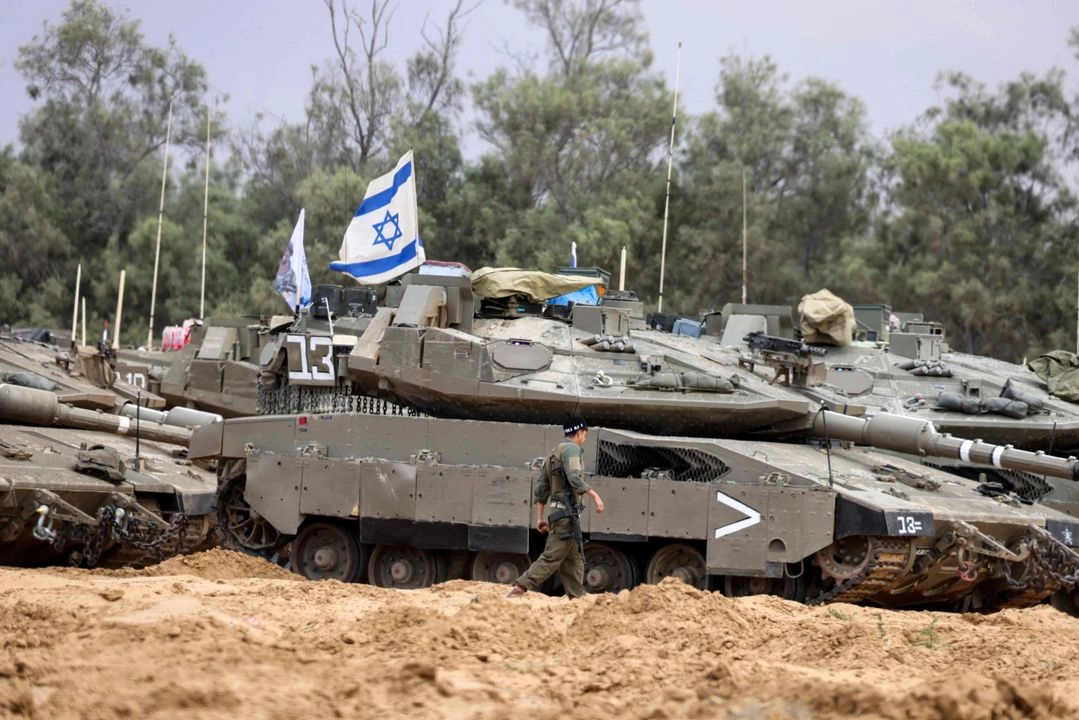 Un soldado israelí camina cerca de tanques desplegados en una posición cercana a la frontera de Israel con Gaza, el 4 de mayo de 2025. Foto