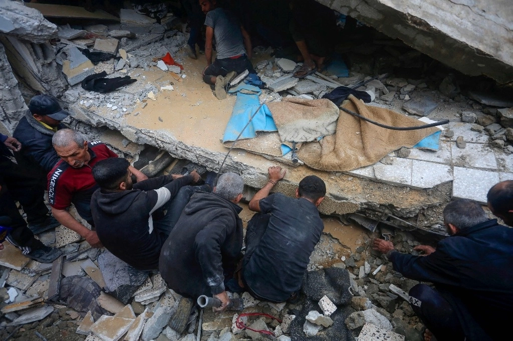 Voluntarios buscan a sobrevivientes de una familia cuya vivienda se desplomó al ser alcanzada ayer por un bombardeo israelí en Deir Balah, en la franja de Gaza. Foto Afp 




