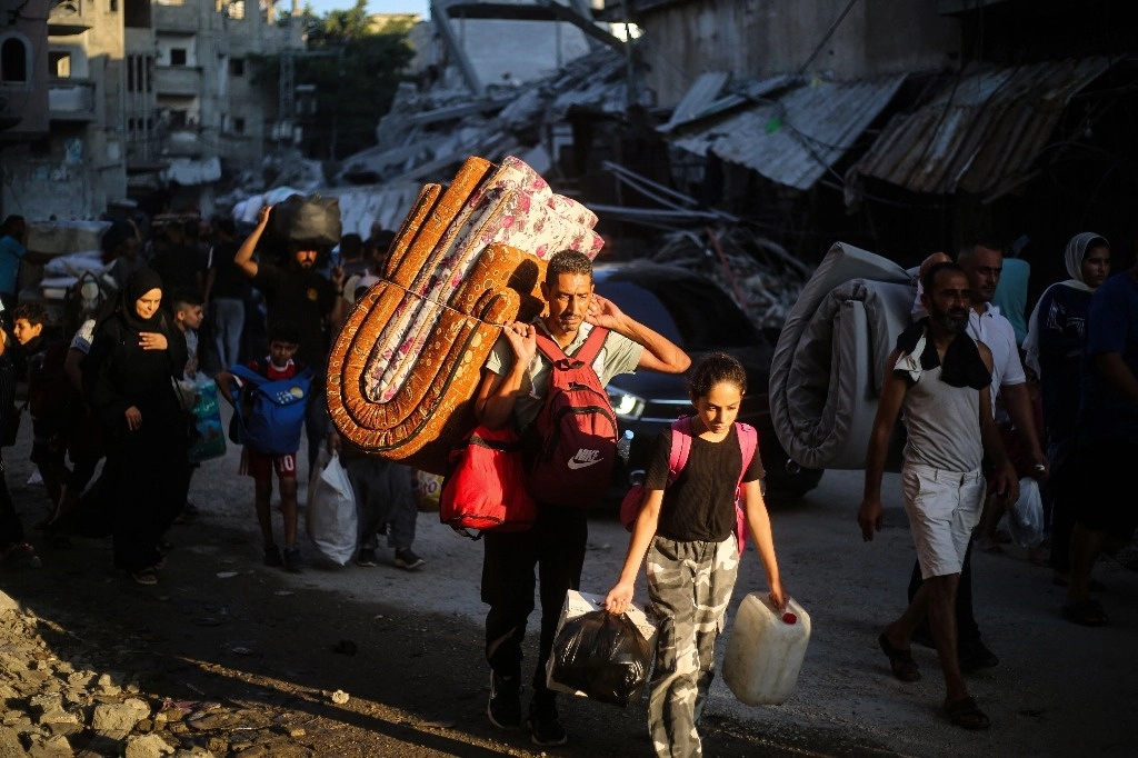Palestinos abandonan el campo de refugiados de Bureij ante los embates de las fuerzas israelíes. Foto Afp