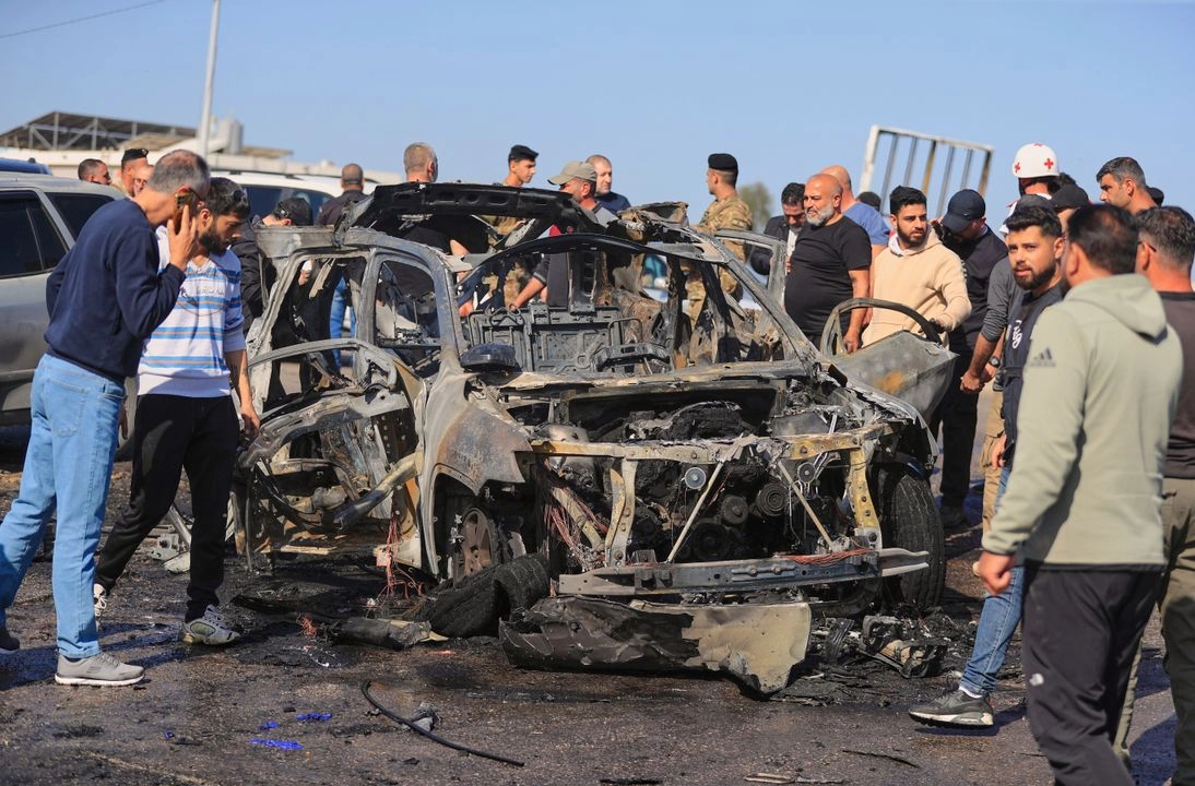 Personas se reúnen cerca de un automóvil calcinado que fue alcanzado por un ataque israelí, en la ciudad costera de Ghazieh, al sur del Líbano, el 18 de abril de 2025. Foto 