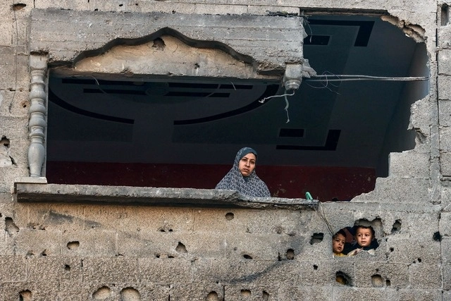 Una mujer palestina y niños observan un bombardeo israelí en Rafah, al sur de Gaza, este viernes. Foto Afp 