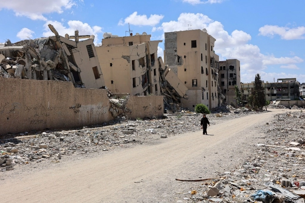 Una mujer palestina camina frente a edificios dañados por los bombardeos israelíes, en Beit Lahia, en el norte de la Franja de Gaza, el 14 de septiembre de 2024. Foto Afp