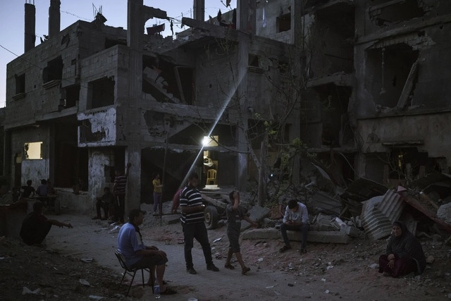Personas a las afueras de sus hogares tras un bombardeo en la ciudad de Bait Hanun. Foto Ap