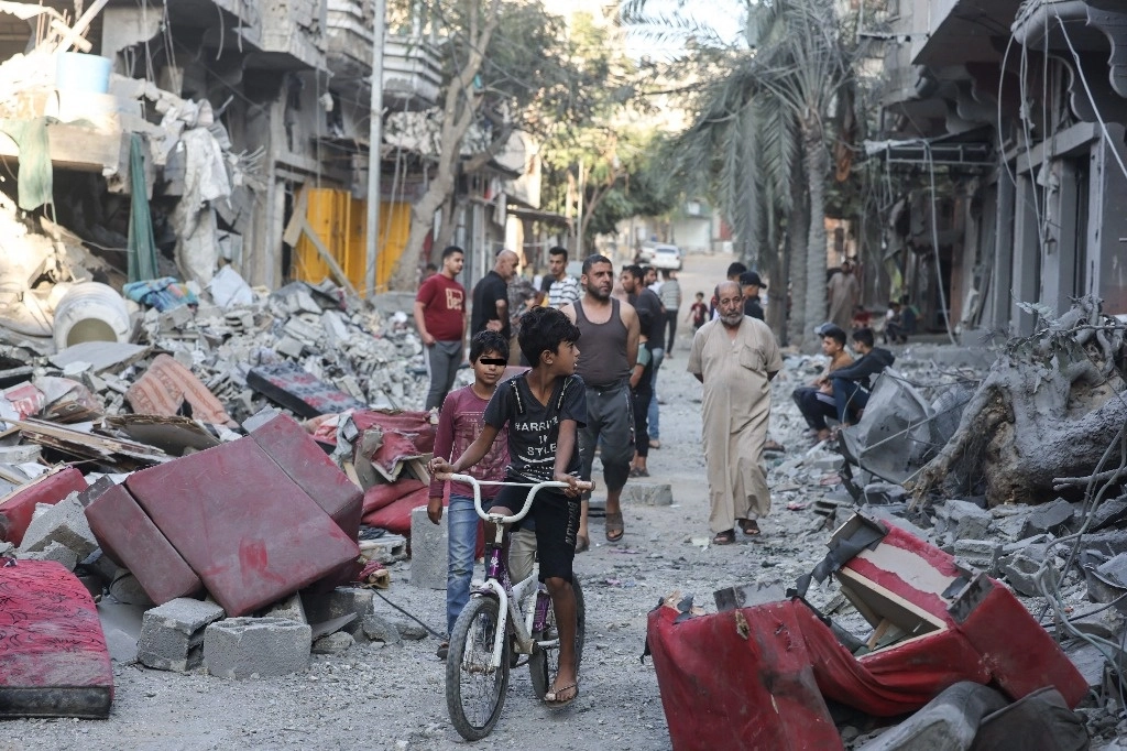Un niño palestino en bicicleta observa los edificios destruidos tras el bombardeo israelí en el campo de refugiados de Nuseirat, en el centro de la Franja de Gaza, a finales de octubre pasado, en medio de las batallas en curso entre Israel y el grupo Hamas. Foto AFP  