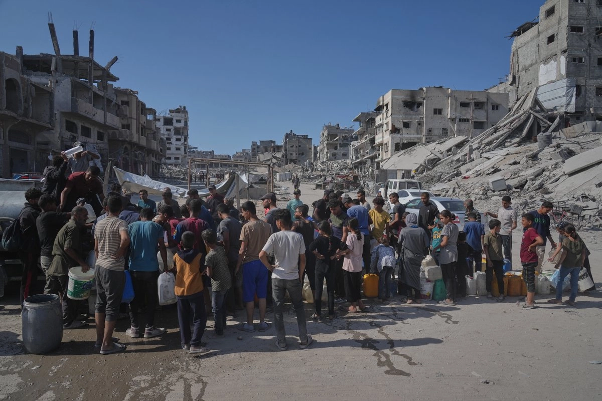 Palestinos recolectan agua de un camión en medio de la destrucción causada por la ofensiva aérea y terrestre israelí en la ciudad de Gaza, el 16 de octubre de 2025. Foto 
