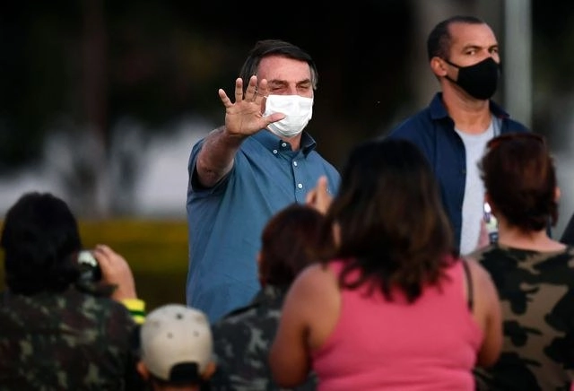 Jair Bolsonaro saluda a sus partidarios en la residencia oficial, en Brasilia. Foto Afp 