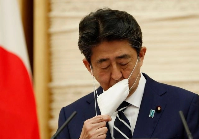 El primer ministro japonés Shinzo Abe se quita el cubrebocas durante una conferencia de prensa este lunes en Tokio. Foto Afp 