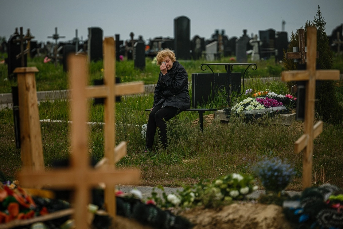 Una mujer visita la tumba de Stanislav Hvostov, de 22 años, un militar ucranio asesinado durante la invasión rusa de Ucrania, en la sección militar del cementerio número 18 de Kharkiv en Bezlioudivka. Foto Afp