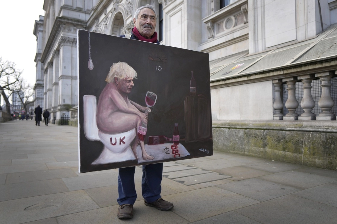 La eliminación de las restricciones contra el coronavirus en Inglaterra ocurren en medio del escándalo por las fiestas del gobierno en el confinamiento. En la imagen, el artista Kaya Mar muestra una pintura crítica contra el primer ministro, Boris Johnson, el 19 de enero de 2022. Foto Ap