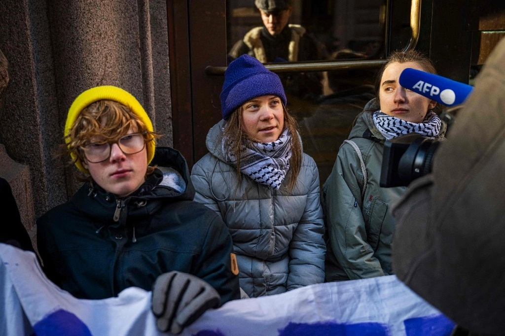 La activista climática sueca Greta Thunberg (2.a izq.) y un grupo de compañeros activistas bloquean las entradas principales del Parlamento sueco durante una protesta por la falta de acción de las autoridades suecas, el 11 de marzo de 2024, en Estocolmo, Suecia. Foto Afp