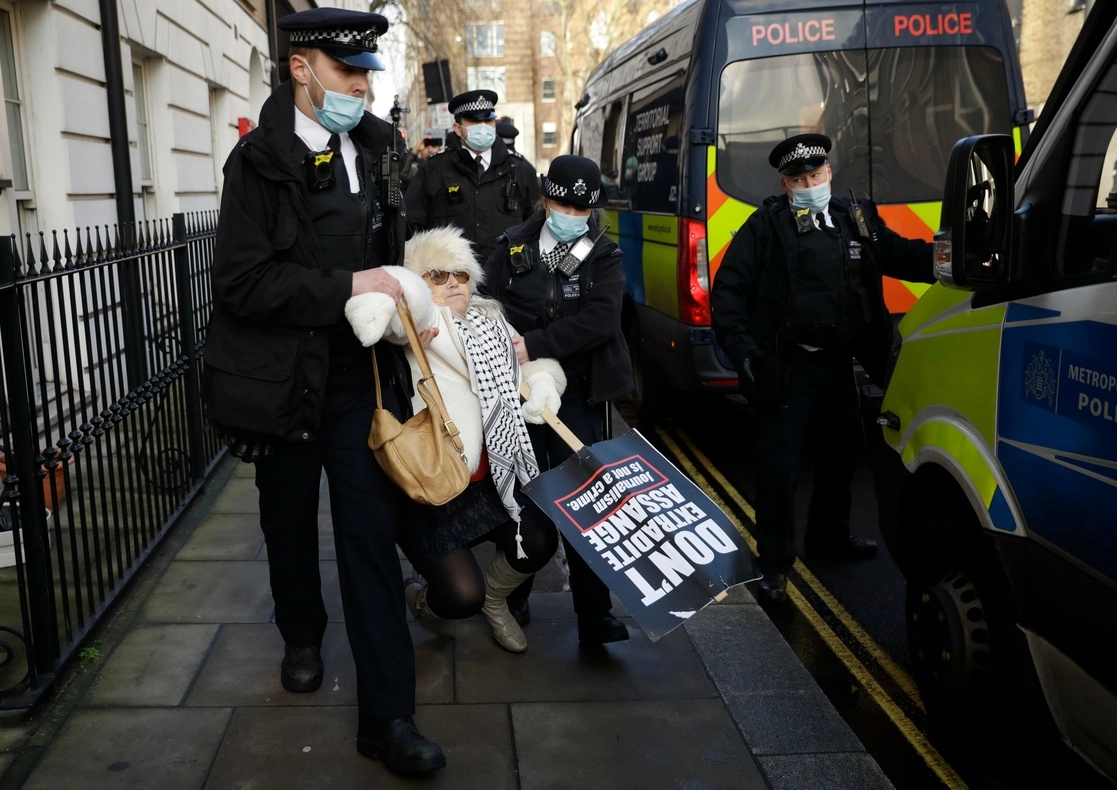 Policías desalojaron a una seguidora de Assange, quien a pesar del confinamiento estaba afuera de la corte durante la audiencia en Londres. Foto Ap