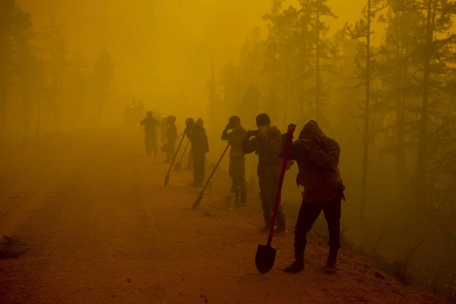 Los voluntarios hacen una pausa mientras trabajan para sofocar un incendio forestal cerca de la aldea de Kyuyorelyakh, en Rusia. Foto Ap / Archivo