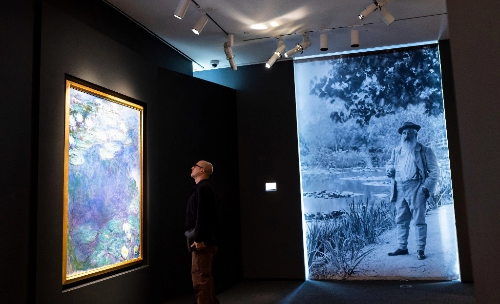 Un hombre observa el cuadro ‘Nympheas’, del artista Claude Monet (a la derecha), previo a una subasta de Sotheby's en Nueva York, el 11 de noviembre de 2024. Foto Ap