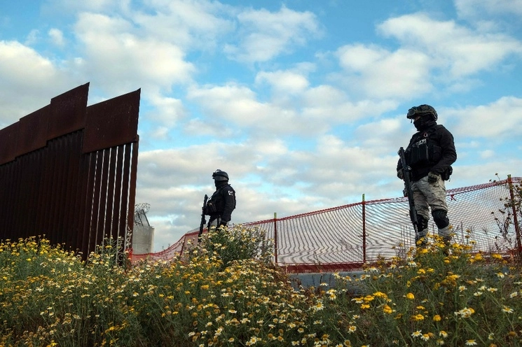 Oficiales de la Guardia Nacional mexicana vigilan una sección abierta del muro fronterizo entre Estados Unidos y México en Tijuana, Baja California. Foto Afp 