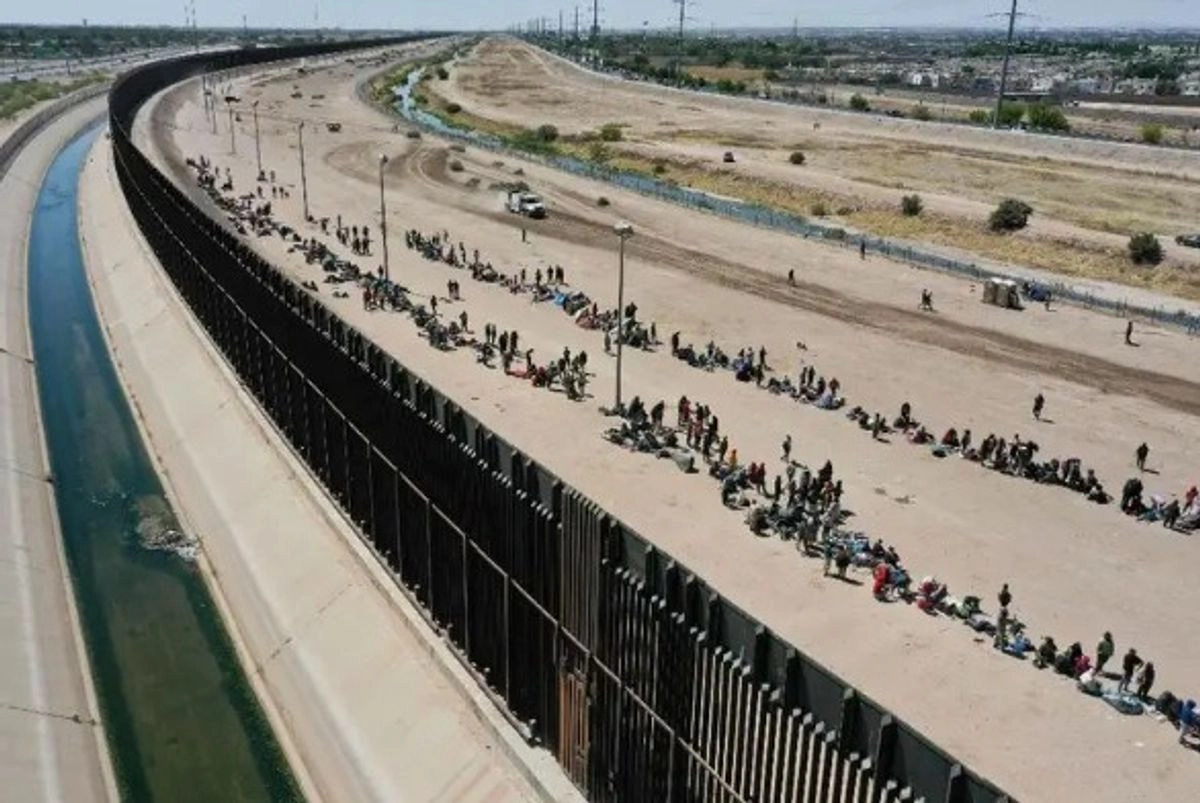 Vista aérea de migrantes que esperan junto al muro fronterizo para presentarse ante agentes de la patrulla fronteriza y pedir asilo en El Paso, Texas.