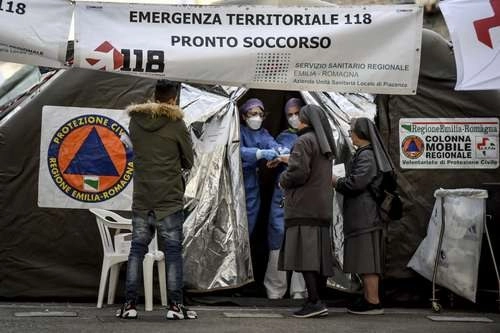 Monjas conversan con paramédicos en una carpa instalada por Protección Civil junto a la sala de emergencias del hospital Piacenza, en el norte de Italia, que ya reporta 17 decesos por el Covid-19.Foto Ap