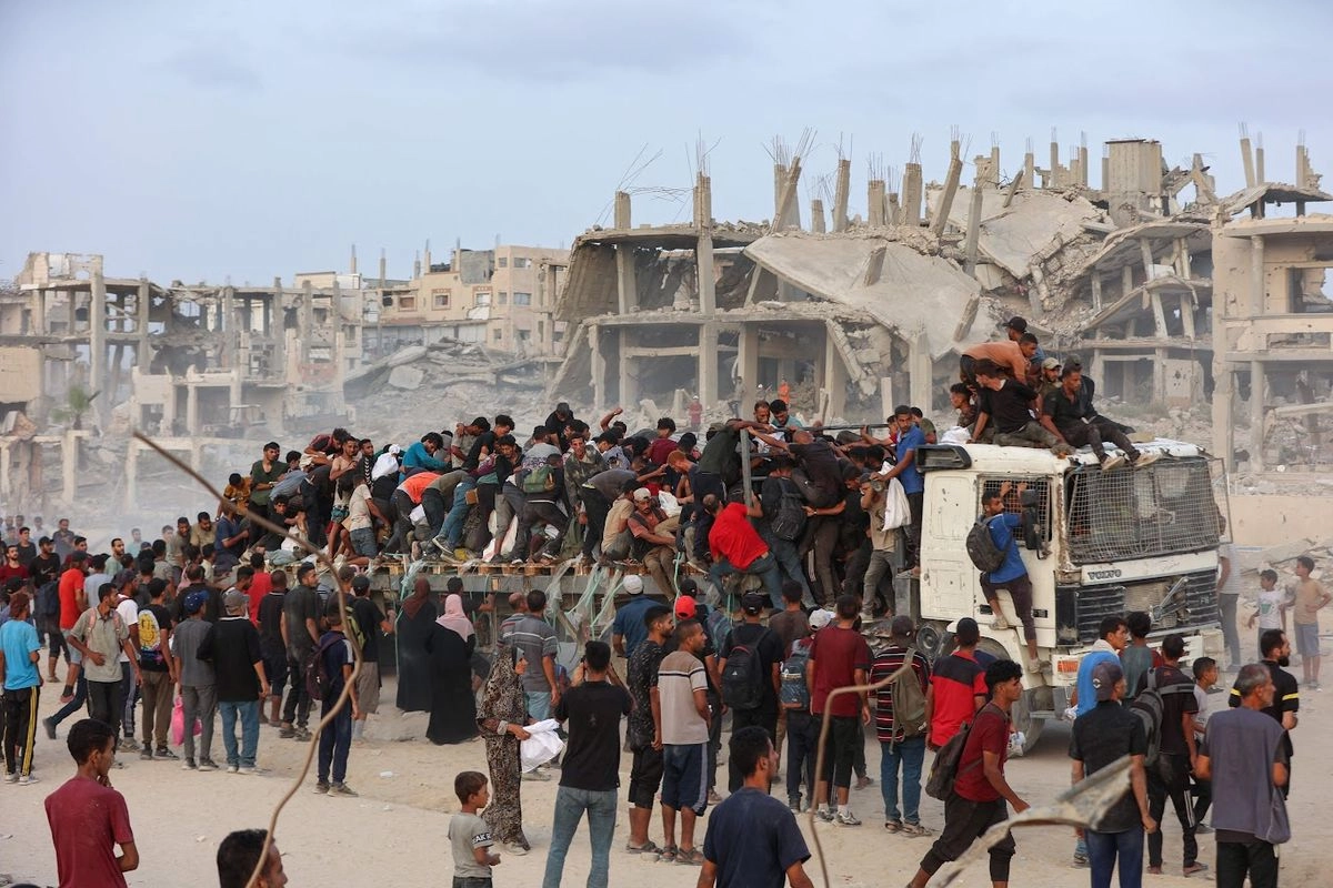 Palestinos se arremolinan en la plataforma de un camión en un sendero costero al oeste de Beit Lahia, en Gaza, después de obtener ayuda, ayer, cuando los cargamentos con alimentos ingresaron a la franja asediada por Israel. Foto 