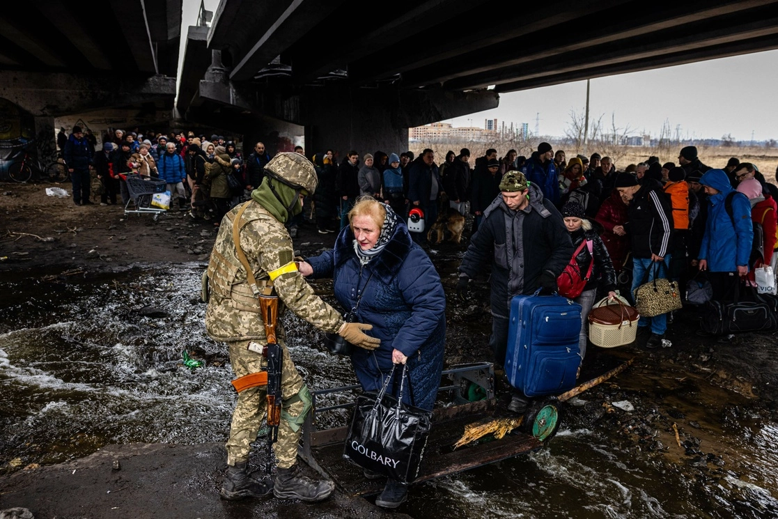 Un militar ayuda a ucranios a huir de la ciudad de Irpin, al noroeste de Kiev, el 7 de marzo de 2022. Foto Afp