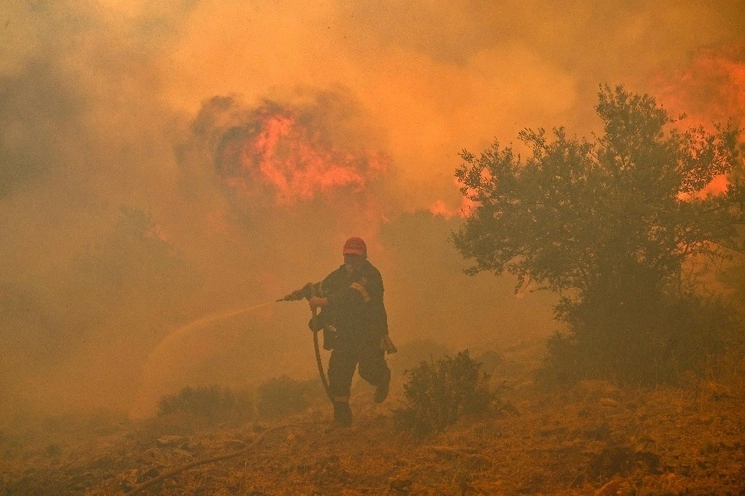 Un bombero huye de las llamas mientras trata de controlar un incendio forestal, el 19 de julio de 2023. Foto Afp 