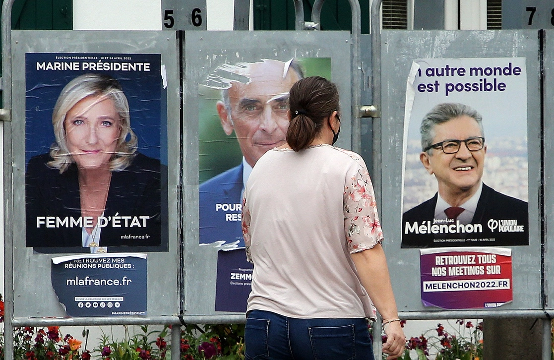 Una mujer camina frente a los carteles de los candidatos presidenciales de la extrema derecha francesa Marine Le Pen y Eric Zemmour, y del líder de extrema izquierda Jean-Luc Melenchon (der.), en Anglet, al suroeste de Francia, el 8 de abril de 2022. Foto Ap