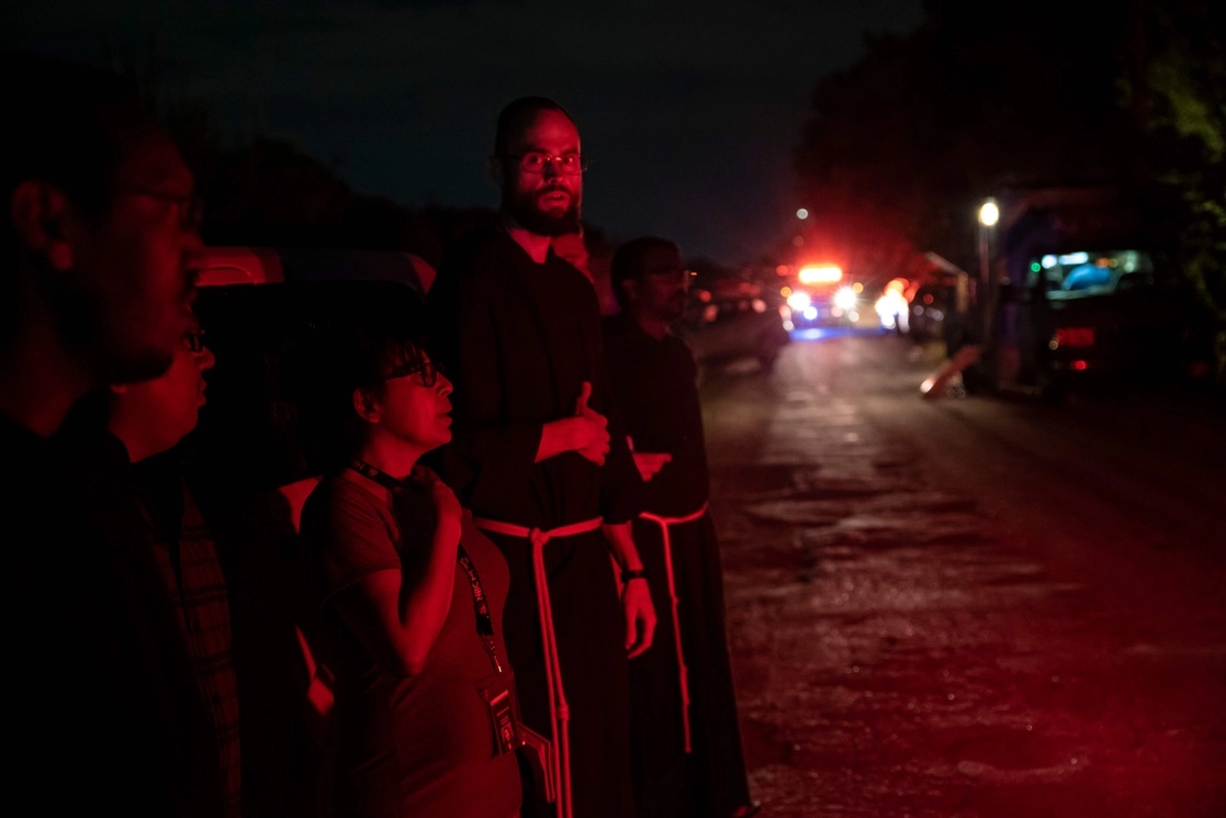 Un sacerdote de la arquidiócesis de San Antonio, Texas, en la escena donde el tráiler fue descubierto ayer con 50 migrantes fallecidos. Foto Afp 