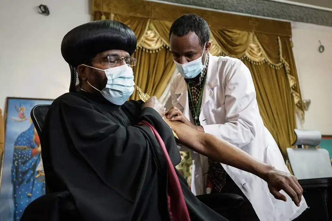 Un sumo sacerdote ortodoxo etíope recibe la primera dosis de la vacuna contra Covid-19 en la sede de la iglesia ortodoxa Tewhdo en Addis Abeba, después de el Ministerio de Salud del país solicitó a todos los líderes religiosos la inoculación obligatoria, el 8 de abril de 2021. Foto Afp