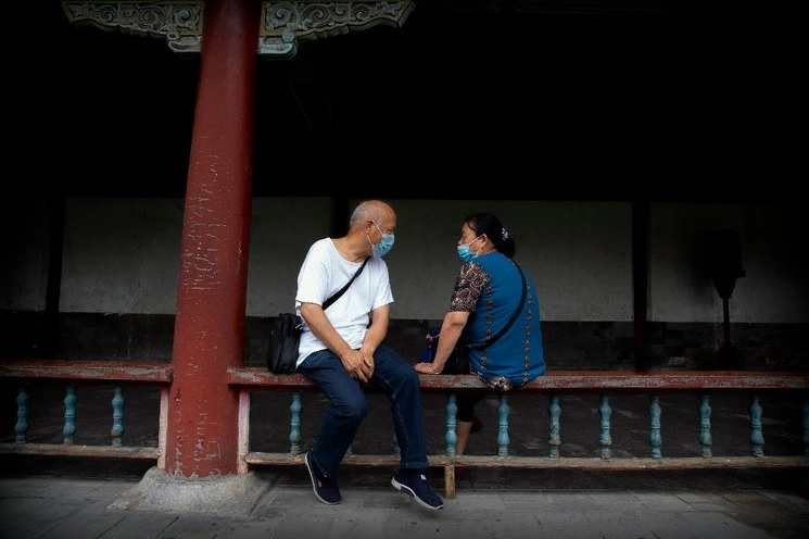 Una pareja se encuentra sentada en una barandilla del Templo del Cielo en Pekín, China. Foto Mark Schiefelbein / Ap