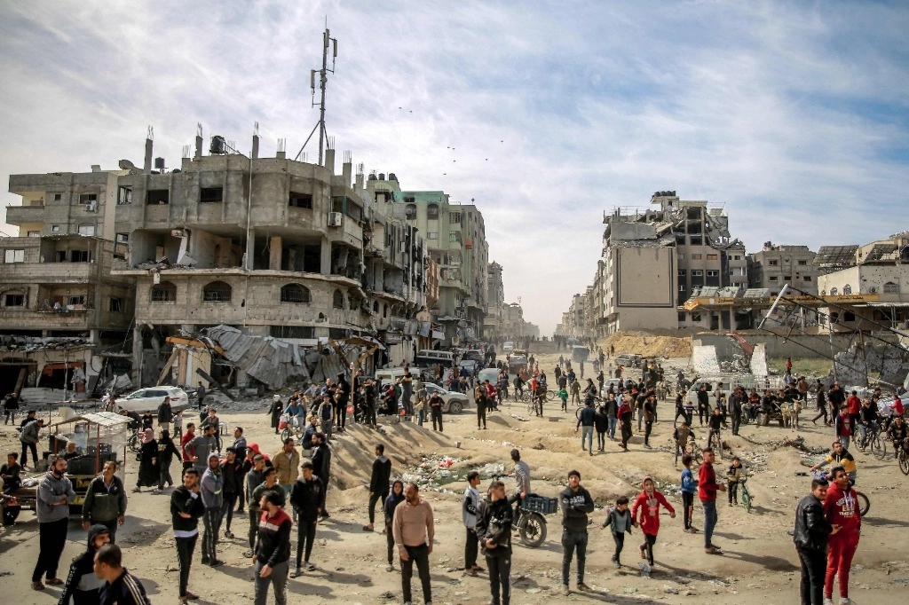 Los palestinos observan a lo lejos la ayuda humanitaria que es lanzada desde el aire en la ciudad de Gaza, el 2 de marzo de 2024. Foto Afp