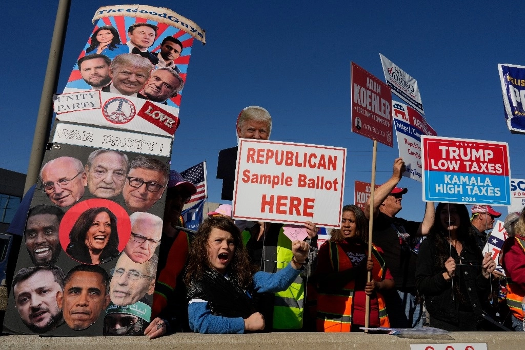 Los partidarios del candidato presidencial republicano, el expresidente Donald Trump, gritan mientras reparten papeletas de muestra republicanas durante la votación anticipada fuera de la Junta Electoral del Condado de Hamilton, el sábado 2 de noviembre de 2024, en Cincinnati. Foto Ap