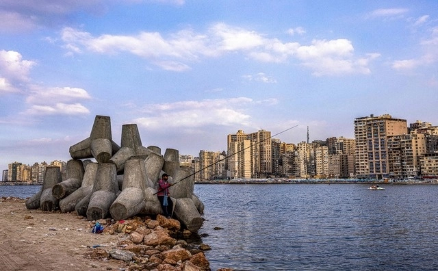 Un hombre pesca junto a bloques de concreto para detener las olas del mar Mediterráneo en la costa egipcia de Alejandría. El calentamiento global ha aumentado los niveles marítimos. Foto Afp