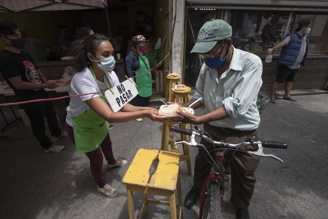 Un hombre recibe alimento de un comedor de beneficencia llamado "olla comunitaria", en la Ciudad de Guatemala, durante la emergencia sanitaria. Foto Ap / Archivo