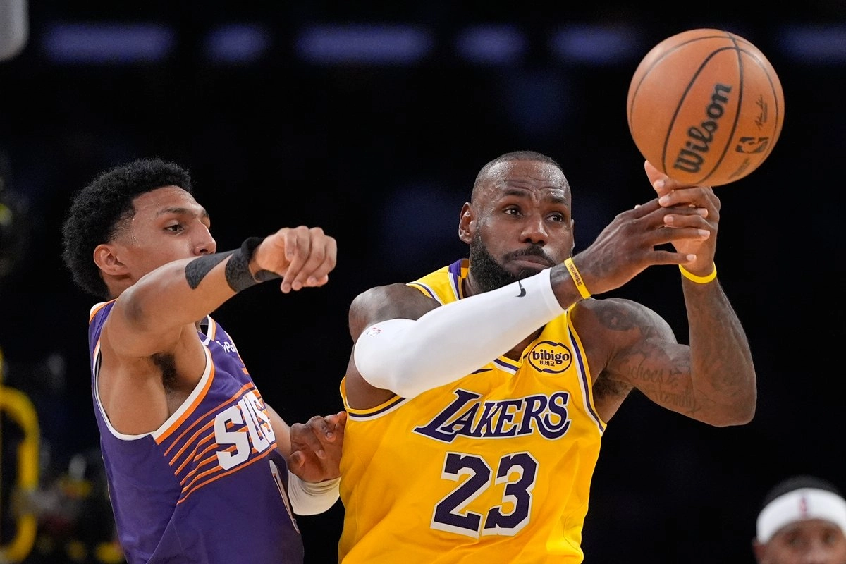 El alero de los Phoenix Suns, Ryan Dunn (izquierda), y el alero de Los Angeles Lakers, LeBron James, intentan un balón suelto durante la segunda mitad de un partido de baloncesto de la NBA el lunes 1 de diciembre de 2025 en Los Ángeles. Foto