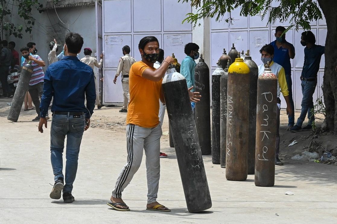 Un hombre mueve un cilindro para rellenarlo de oxígeno en un establecimiento de Nueva Delhi, India, el 12 de mayo de 2021. Foto Afp