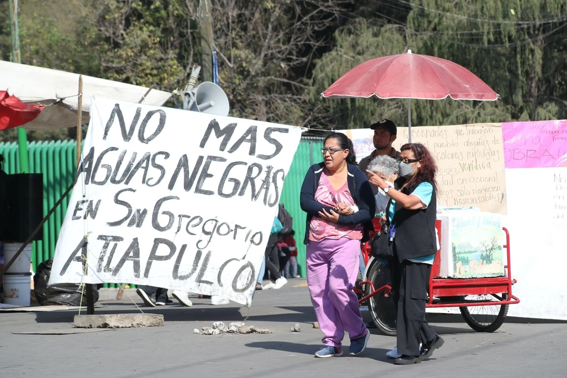 Personas se movilizan entre el bloqueo que mantienen habitantes del pueblo de San Gregorio Atlapulco, en la alcaldía Xochimilco, para continuar con sus actividades cotidianas y económicas, en la Ciudad de México, el 8 de diciembre de 2022. Foto Luis Castillo