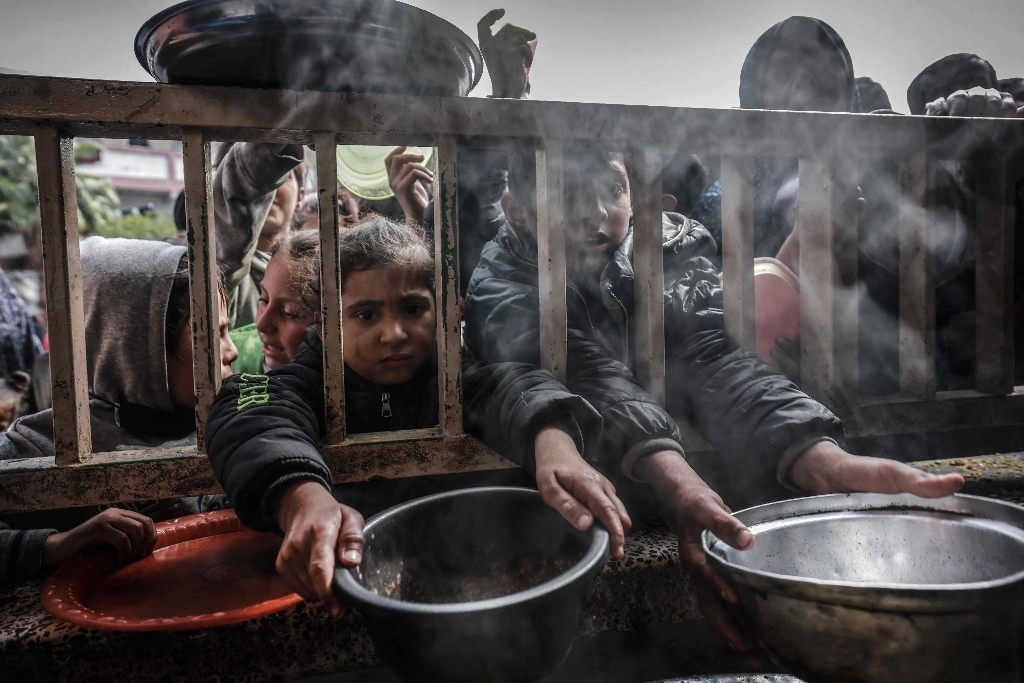 Niños palestinos desplazados a la espera de comida en una escuela en Rafá, el 19 de febrero de 2024. Foto Afp