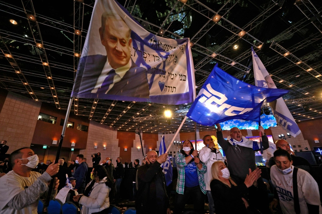 Los partidarios de Likud ondean banderas con el primer ministro Benjamin Netanyahu, mientras reaccionan en la sede de la campaña, en Jerusalén el 23 de marzo de 2021. Foto Afp