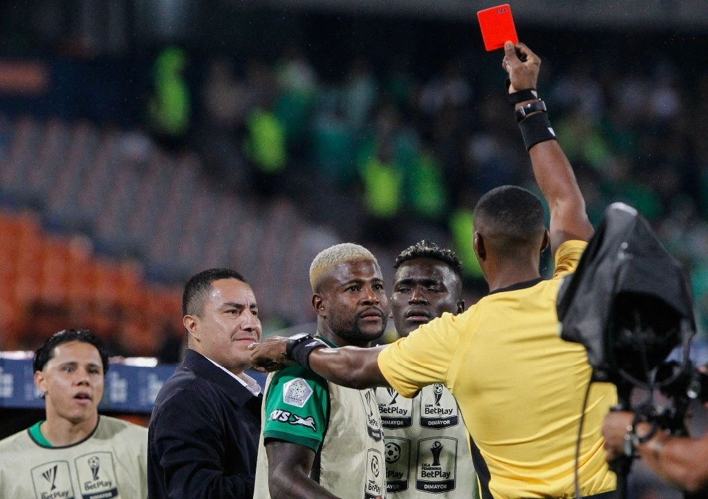 El árbitro Diego Ulloa muestra una tarjeta roja al entrenador mexicano del Atlético Nacional, Efraín Juárez (2-L), durante el partido semifinal cuadrangular de la liga colombiana de fútbol entre Nacional y Santa Fe. Foto Afp