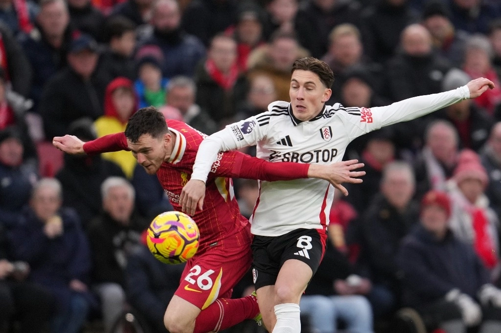 Andrew Robertson de Liverpool y Harry Wilson de Fulham compiten por conseguir la posesión del balón en duelo de la fecha 16 de la Liga Premier, en el estadio Anfield, el 14 de diciembre de 2024. Foto Ap