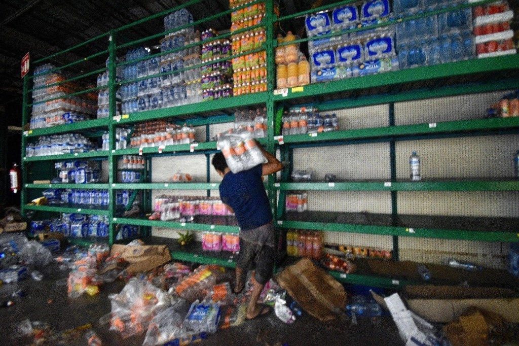 Un hombre recoge comestibles en un supermercado saqueado después del paso del huracán 'Otis' en Acapulco, Guerrero, el 25 de octubre de 2023. Foto Afp
