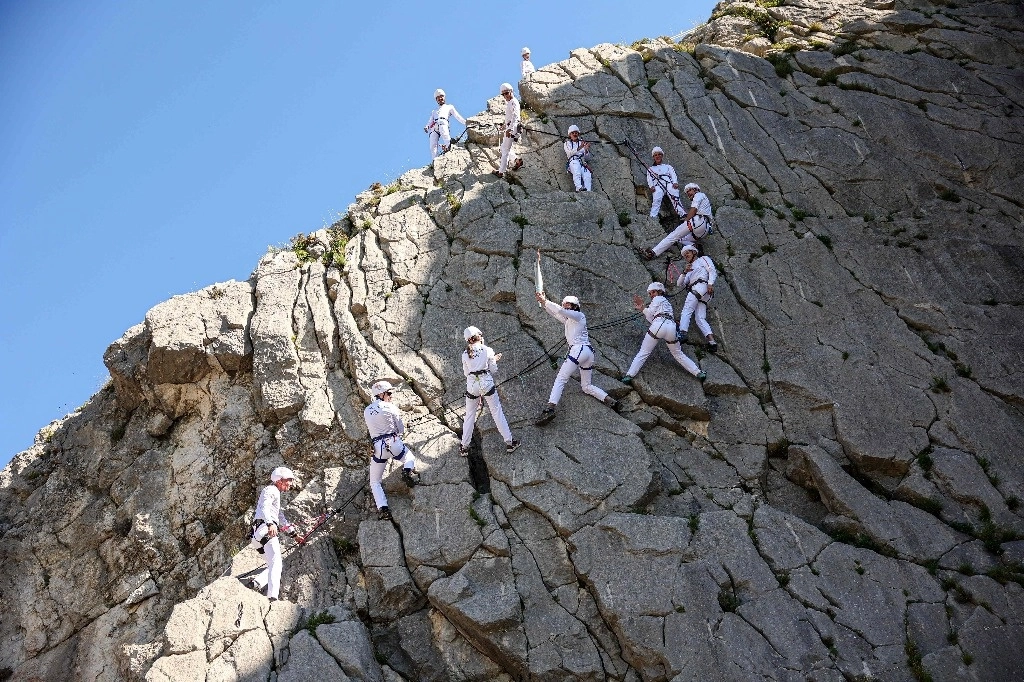 Miembros de un colectivo de escaladores formado por 24 portadores de la antorcha pasan el fuego olímpico a través de la montaña Rocher de la Baume en Sisteron, al de sureste de Francia, el 11 de mayo de 2024. Foto Afp