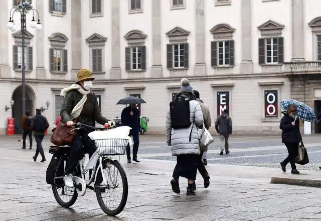 Una mujer se traslada en bicicleta en Milán, usando un tapabocas para evitar el contagio del coronavirus. Foto Afp 