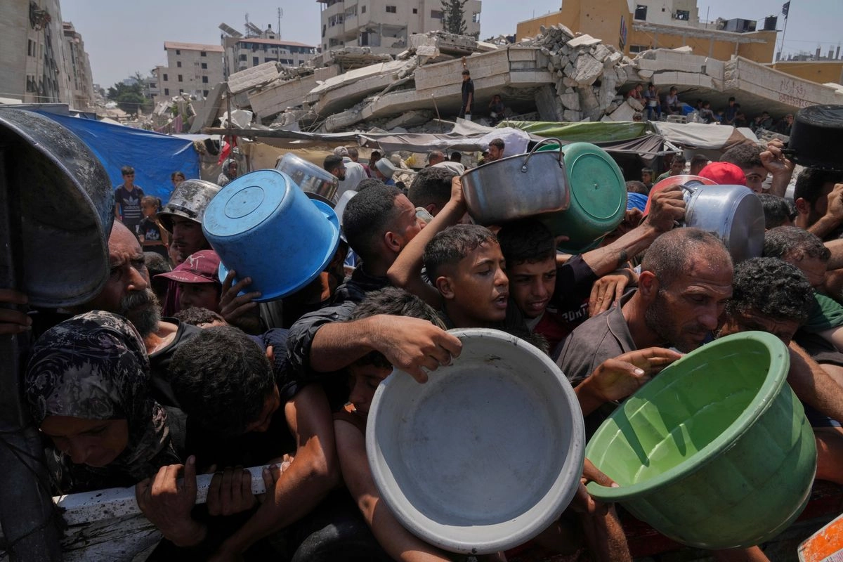 Palestinos luchan por conseguir alimentos donados en un comedor comunitario en la ciudad de Gaza, el 26 de julio de 2025. Foto 