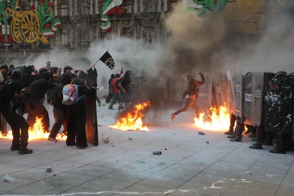 Personas encapuchadas agreden a elementos policíacos durante la marcha por el 2 de octubre en CDMX. Foto

