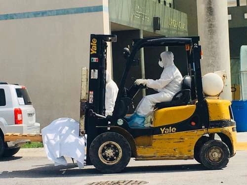 Un trabajador del hospital general Doctor Alfredo Pumarejo, en Matamoros, Tamaulipas, traslada en un montacargas el cuerpo de uno de los fallecidos por Covid-19 a la caja de un tractocamión con sistema de enfriamiento, donde se almacenan por decenas a la espera de ser incinerados en los dos crematorios autorizados por las autoridades de Salud. Foto Julia Le Duc