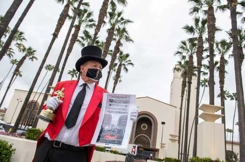 Gregg Donovan sostiene una estatuilla falsa del Óscar y un cartel de una película frente a Union Station durante los preparativos para los premios de la Academia. Foto Afp