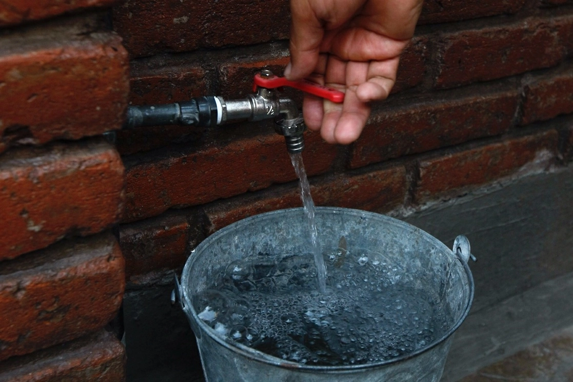 Persona llena un balde de agua en imagen de archivo. Foto Roberto García 