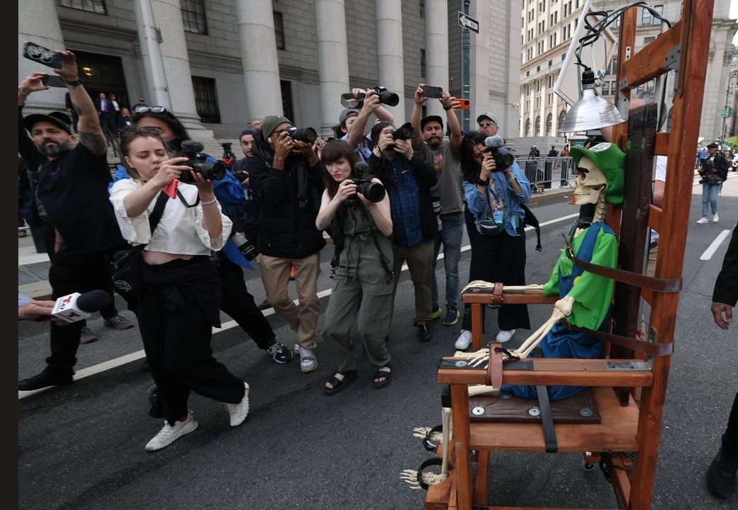 En la imagen, periodistas toman fotografías de la nueva obra del artista estadunidense Scott LoBaido, durante el juicio de Luigi Mangione en el tribunal federal de Nueva York por una acusación formal de cuatro cargos por el asesinato del director ejecutivo de United Healthcare, Brian Thompsonm, el 25 de abril de 2025.