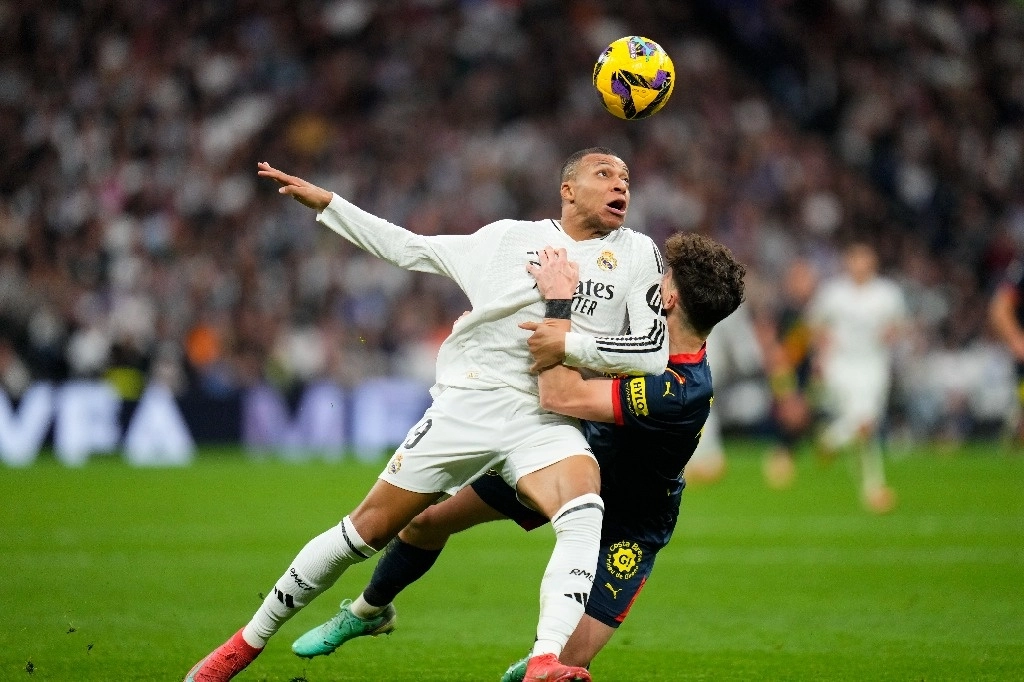 Kylian Mbappé, del Real Madrid, a la izquierda, y Ladislav Krejci, del Girona, disputan el balón durante el partido de la Liga española de fútbol entre el Real Madrid y el Girona en el estadio Santiago Bernabéu en Madrid, España, el 23 de febrero de 2025. Foto Ap