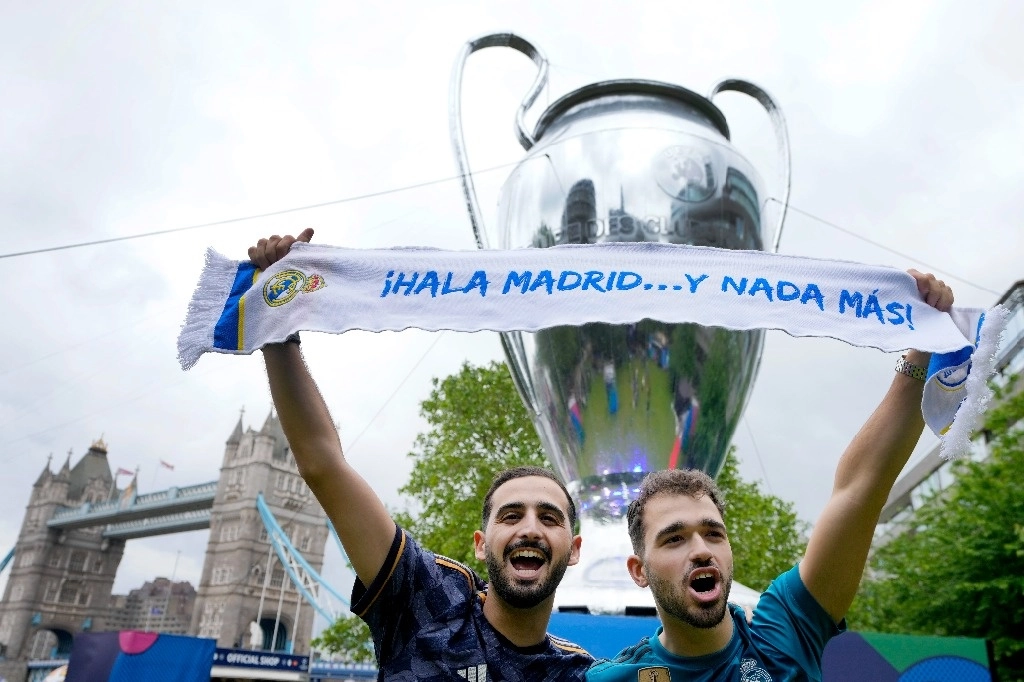 Aficionados posan frente a una copia del trofeo de la Liga de Campeones en Londres, Inglaterra. Foto Ap