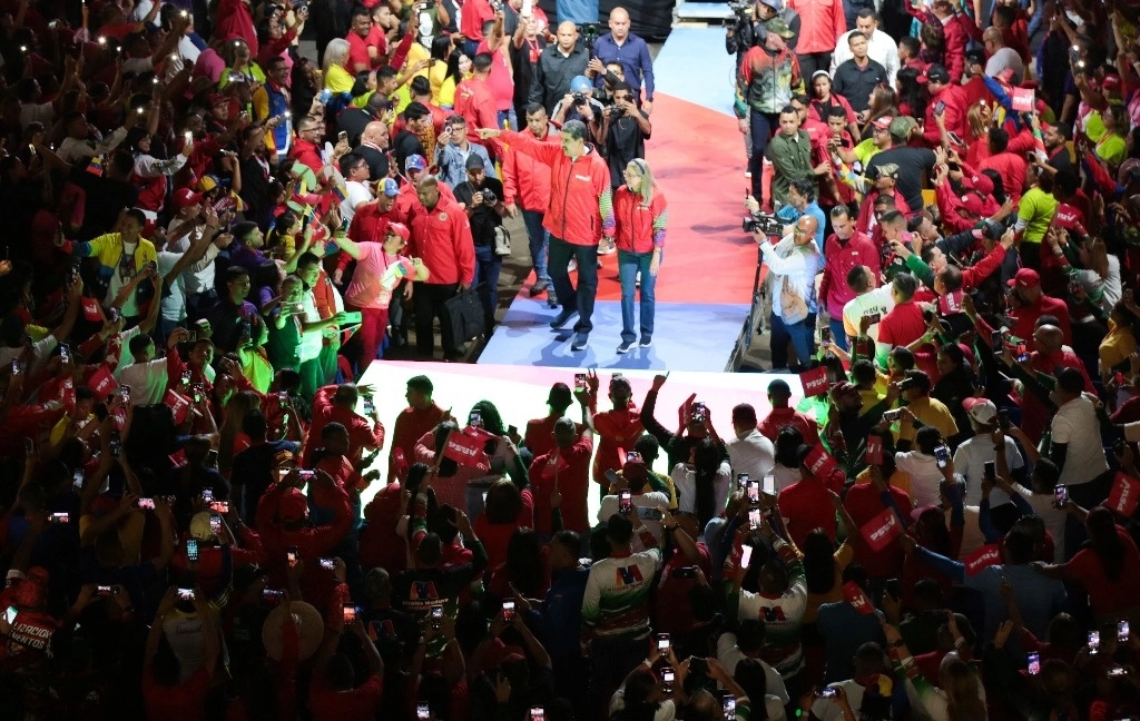 El presidente venezolano, Nicolás Maduro (centro), acompañado por su esposa, Cilia Flores, saluda a sus seguidores  para anunciar su candidatura con el Partido Socialista Unido de Venezuela (PSUV) en el estadio Poliedro. Foto Afp